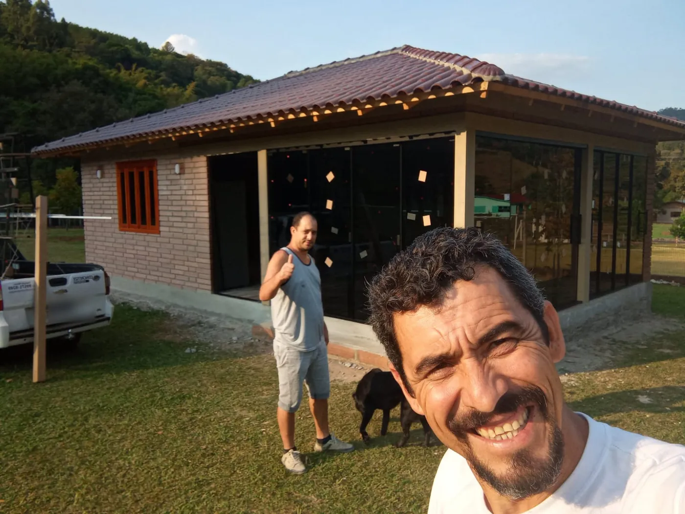 Selfie em frente a uma obra com fechamento em vidro, com um colega ao fundo