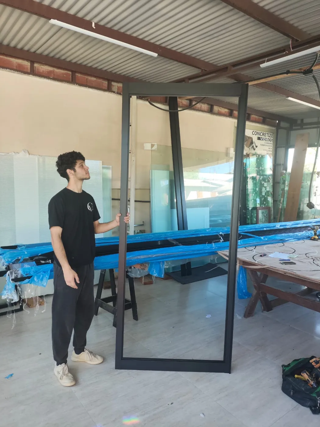 Roger, sócio da Concretize, com um caixilho de alumínio preto recém-montado