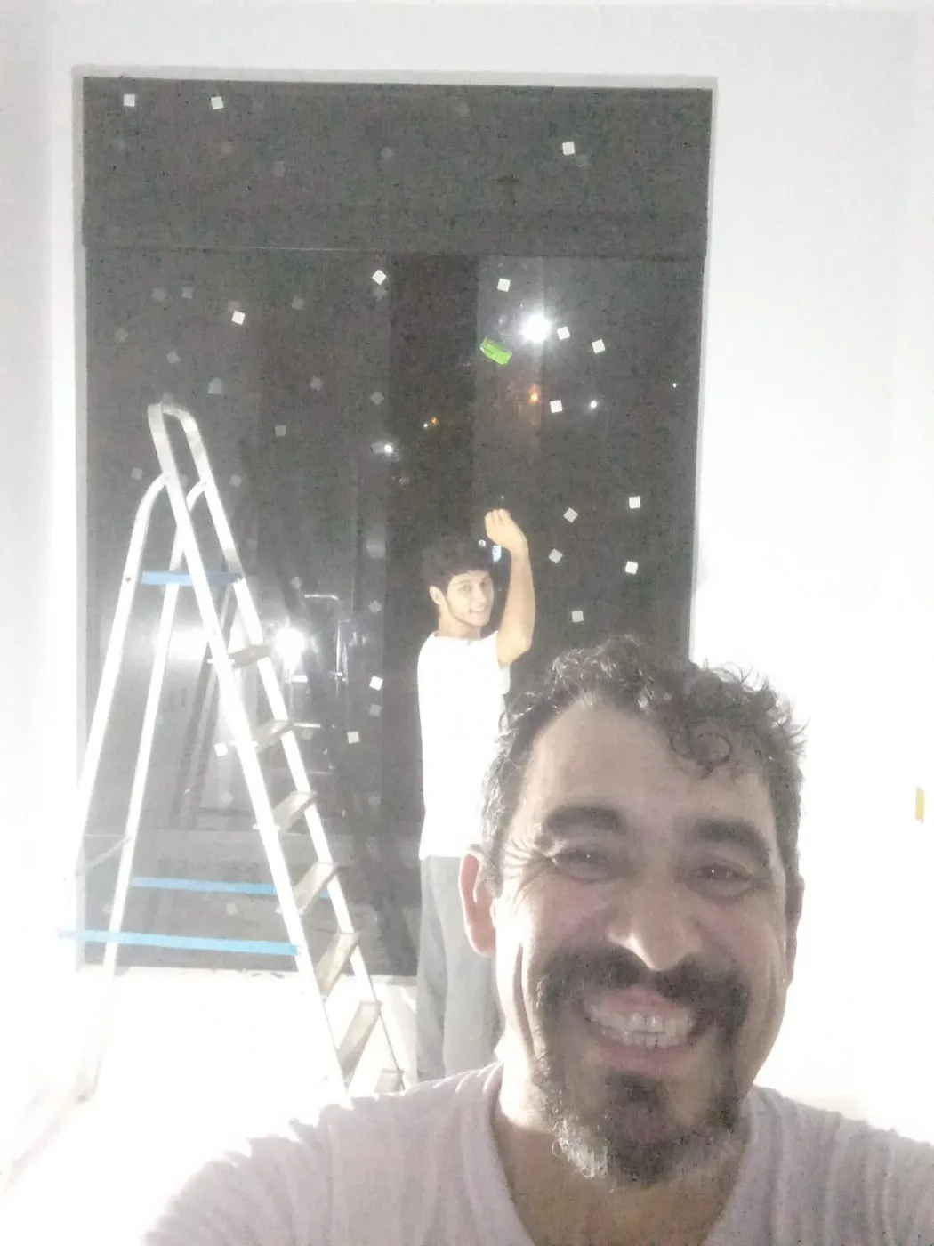 Ezequiel Ribeiro e um colega na instalação de uma porta de vidro temperado