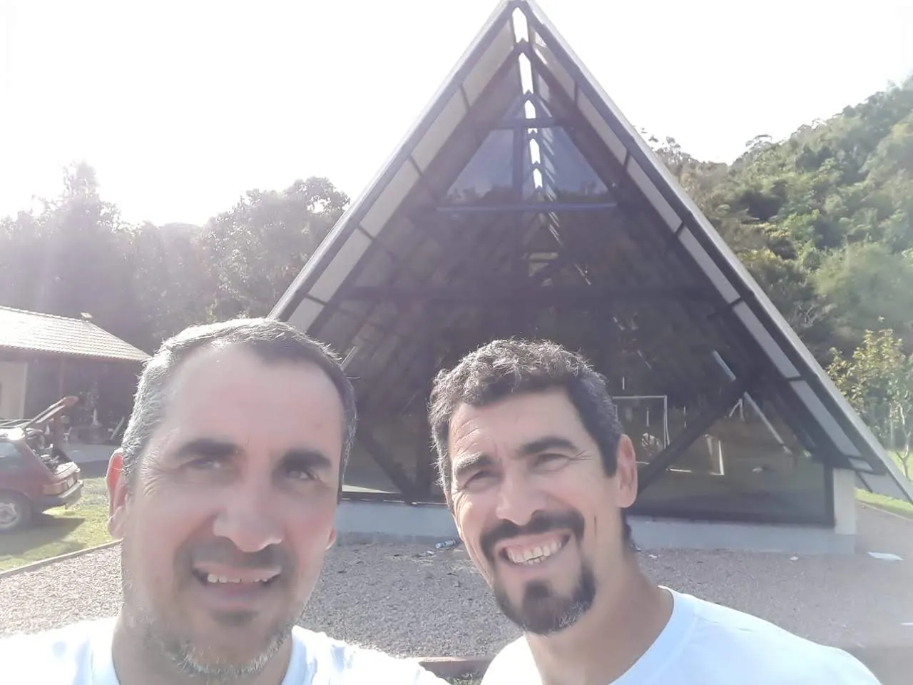 Ezequiel Ribeiro e a primeira pessoa que trabalhou com ele, em frente a um chalé com fechamento em vidro