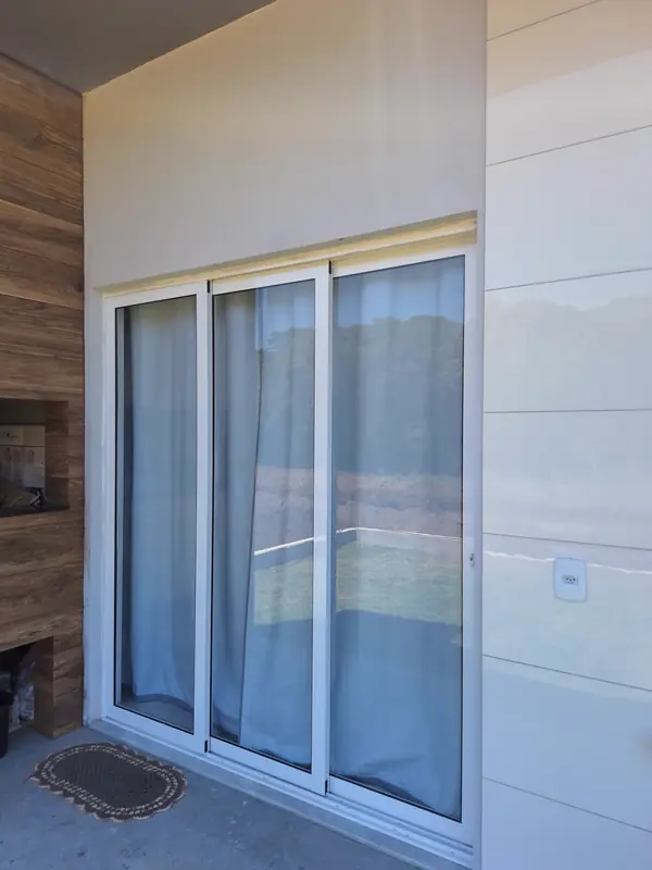 Porta de correr em alumínio branco com vidro, instalada em varanda residencial