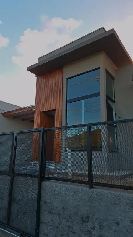 Casa com torre revestida de madeira e esquadria alta de alumínio preto