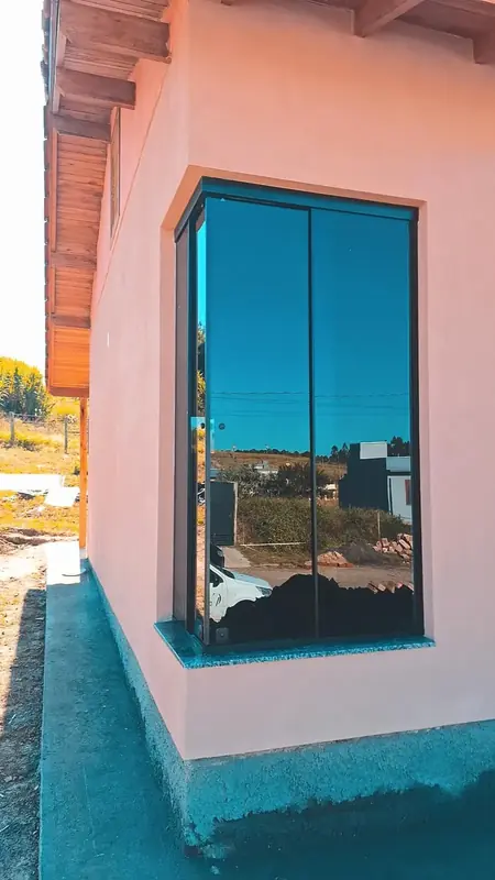 Janela alta de alumínio preto com vidro refletindo a paisagem