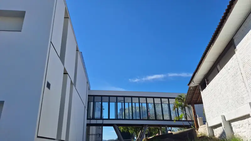 Hospital Bom Jesus: passarela envidraçada entre blocos, sob céu azul