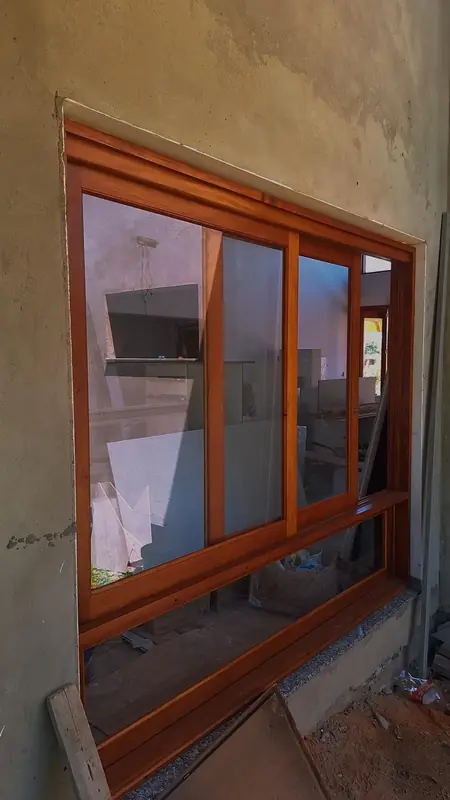 Janela de madeira com vidro instalado, em obra