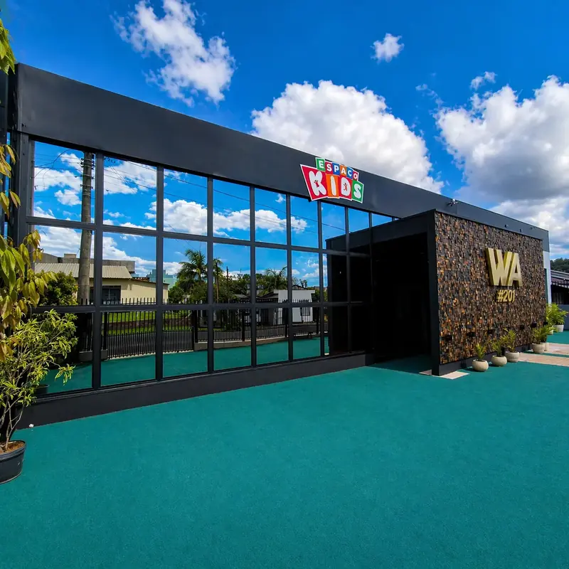 Fachada comercial em vidro com perfis pretos, sob céu azul