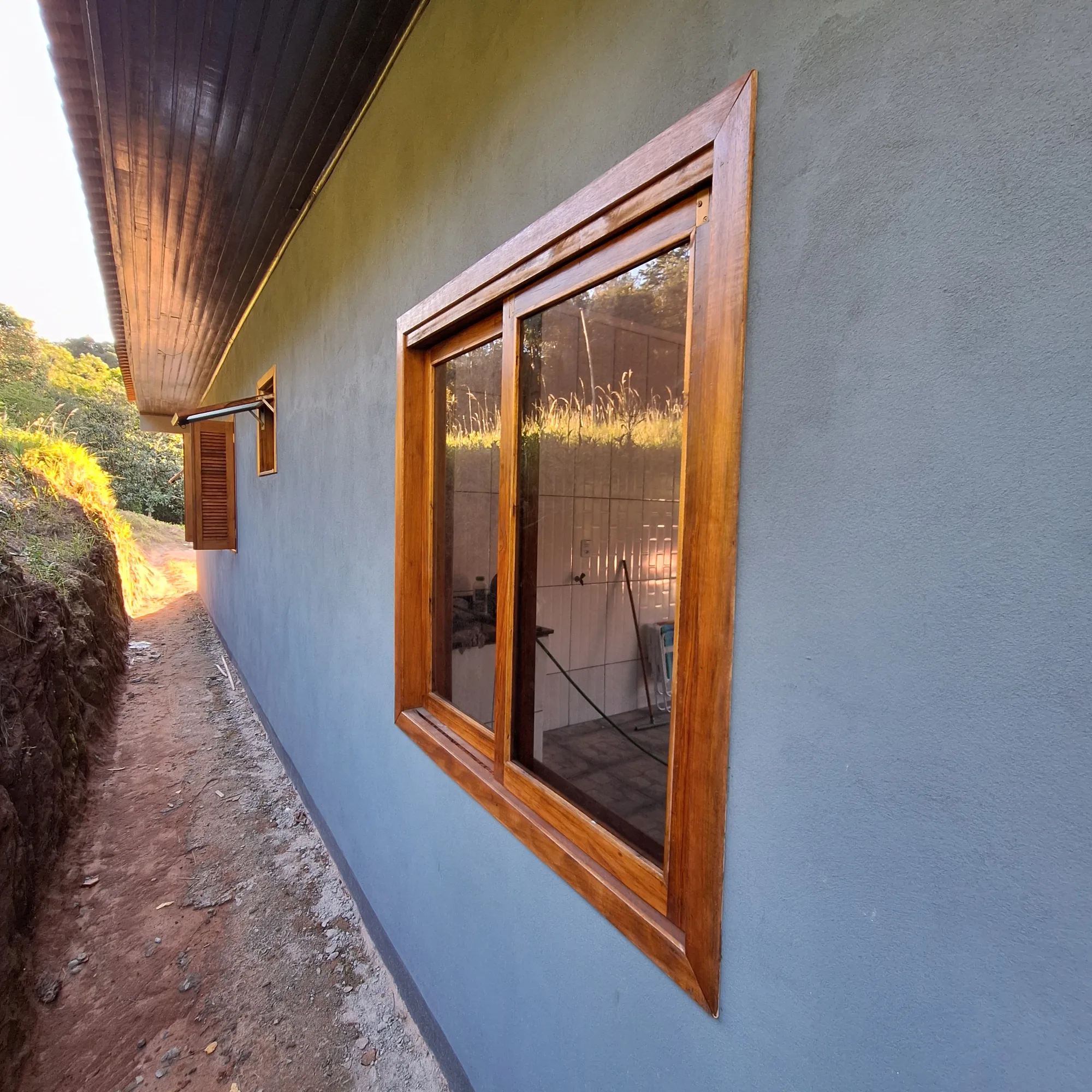 Janela de madeira com vidro instalado em fachada de casa, ao entardecer